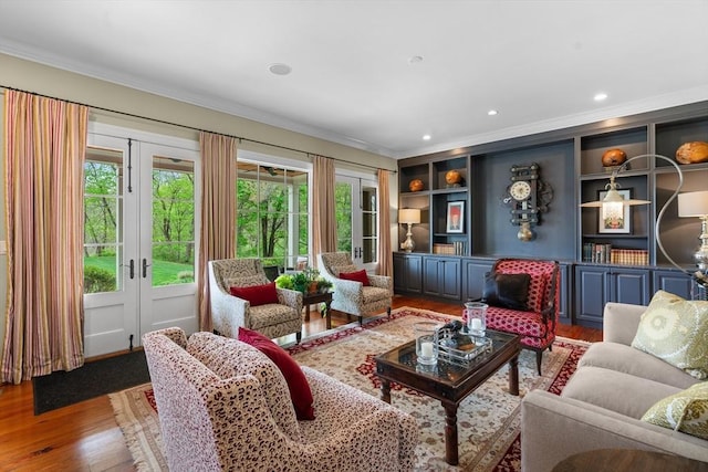 living area with crown molding, plenty of natural light, wood finished floors, and french doors