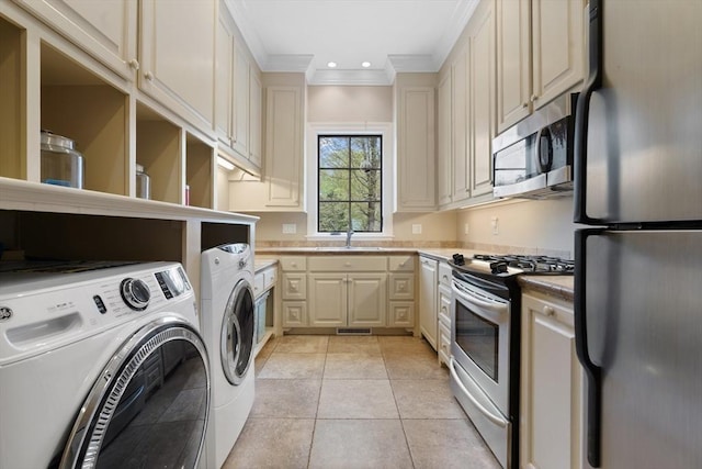clothes washing area featuring washing machine and clothes dryer, crown molding, laundry area, a sink, and visible vents