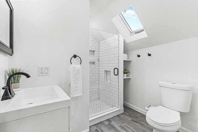 full bathroom featuring toilet, baseboards, lofted ceiling with skylight, a shower stall, and a sink