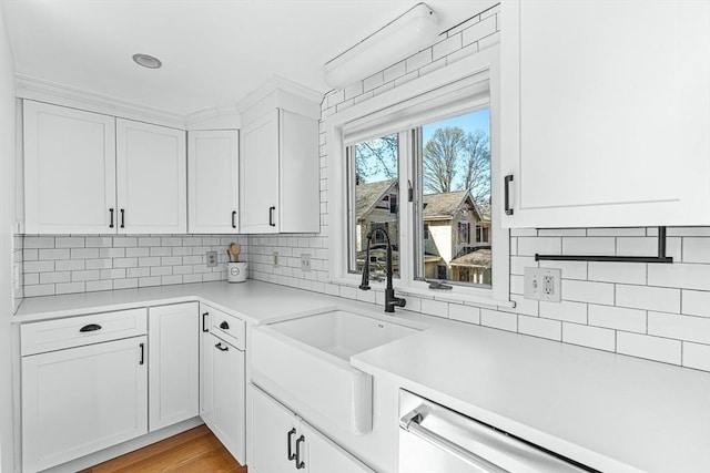 kitchen featuring backsplash, white cabinetry, a sink, and light countertops