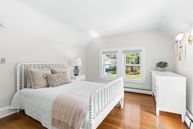 bedroom with wood finished floors, a baseboard heating unit, and vaulted ceiling