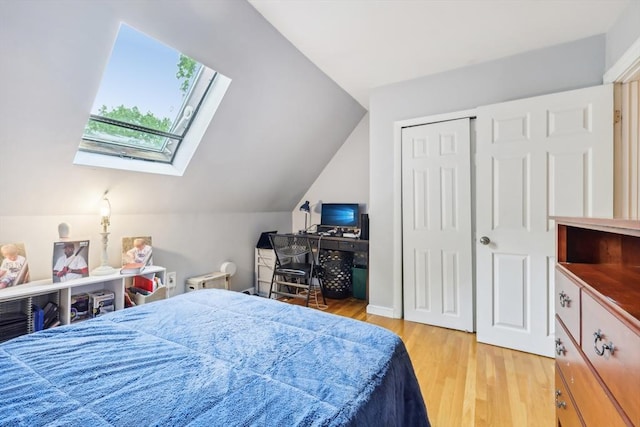 bedroom with lofted ceiling with skylight, a closet, and light wood-style flooring