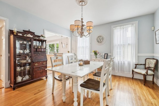 dining space featuring baseboards, a notable chandelier, and light wood-style floors