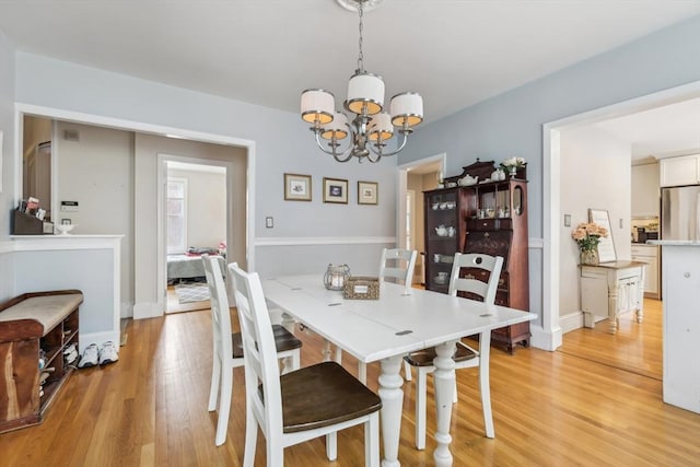dining room featuring light wood finished floors and a notable chandelier