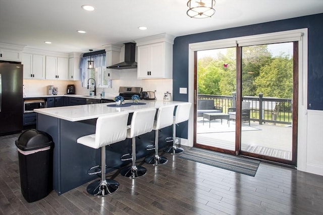 139 Barneyville Rd, Swansea, MA 02777 - kitchen with wall chimney exhaust hood, stainless steel appliances, a sink, a peninsula, and white cabinetry
