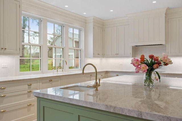 kitchen featuring light stone countertops, decorative backsplash, and a sink