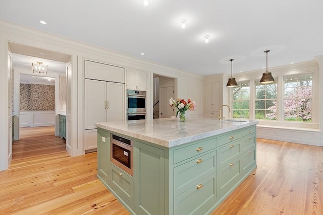 kitchen featuring built in microwave, green cabinets, ornamental molding, a decorative wall, and light wood-style flooring