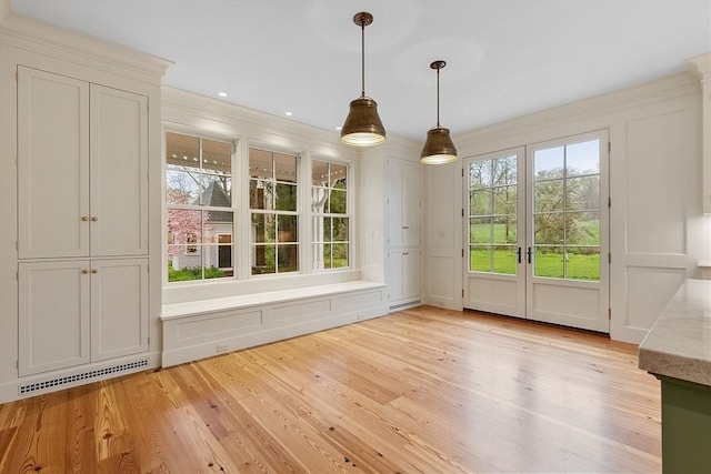 unfurnished dining area with french doors, a decorative wall, light wood-type flooring, and visible vents