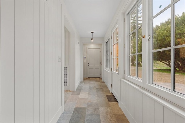 corridor with baseboards, visible vents, and stone tile floors
