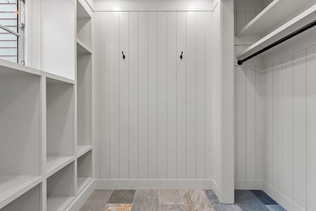 walk in closet featuring stone finish floor