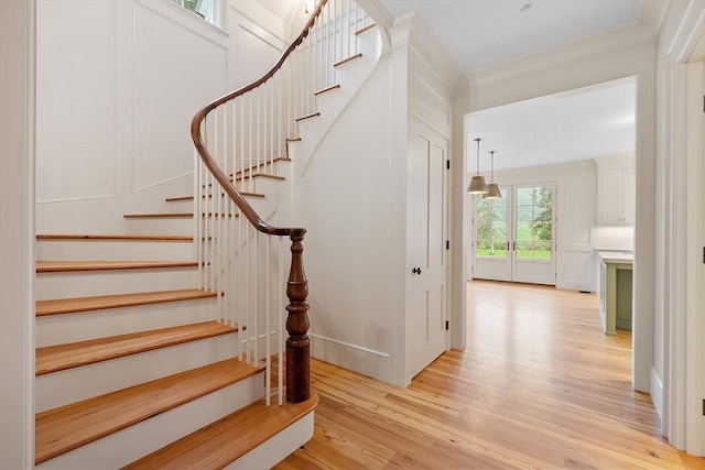 staircase featuring ornamental molding and wood finished floors