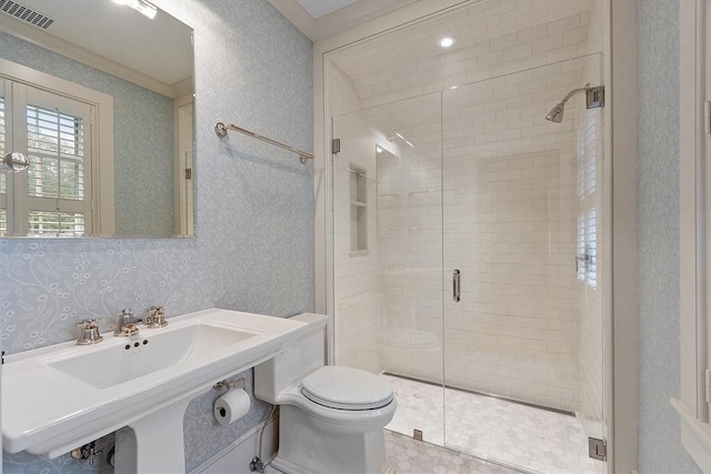 bathroom with a sink, toilet, wallpapered walls, a shower stall, and visible vents