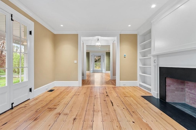 unfurnished living room with crown molding, baseboards, built in shelves, and hardwood / wood-style floors