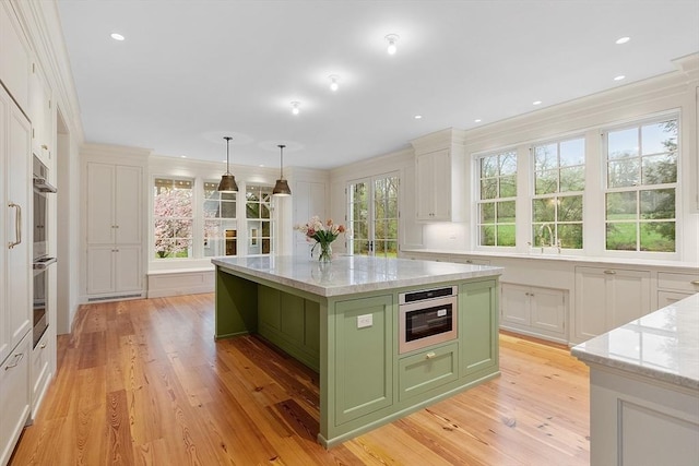 kitchen featuring green cabinetry, light stone counters, a wealth of natural light, and light wood-style flooring
