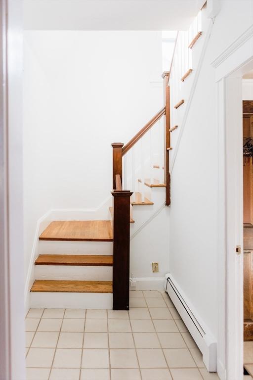 stairway with baseboard heating and tile patterned flooring