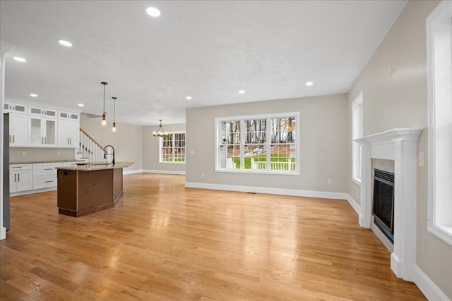 70 Princeton St, Holden, MA 01522 - unfurnished living room with light wood finished floors, a fireplace, recessed lighting, and an inviting chandelier