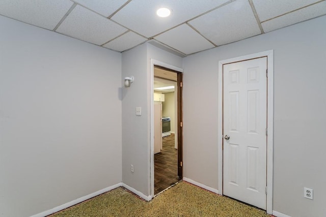 interior space featuring a paneled ceiling and baseboards