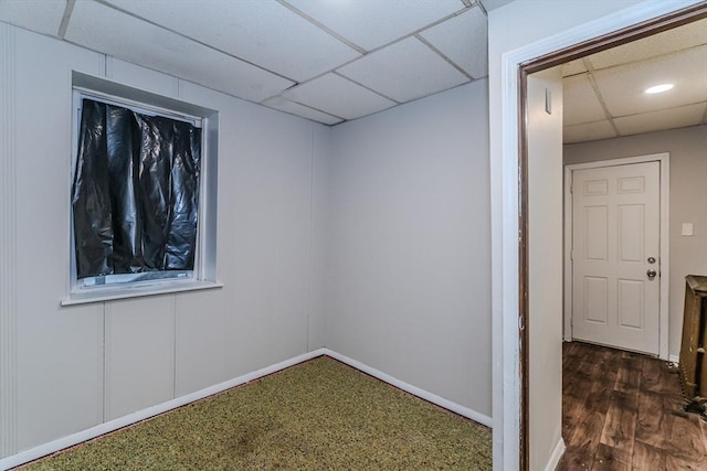 spare room with dark wood-type flooring, a drop ceiling, and baseboards