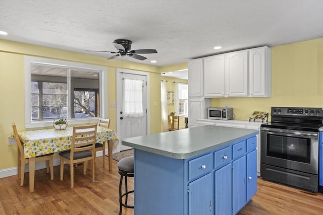 kitchen with blue cabinetry, electric range, a center island, light hardwood / wood-style floors, and white cabinets