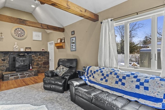 living room with vaulted ceiling with beams, hardwood / wood-style floors, and a wood stove