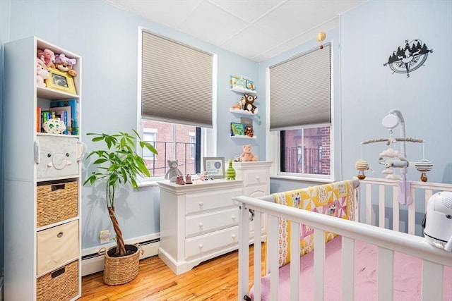 bedroom with a nursery area and light wood-type flooring