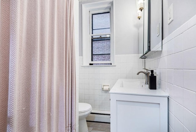 bathroom featuring a baseboard heating unit, vanity, tile walls, toilet, and walk in shower