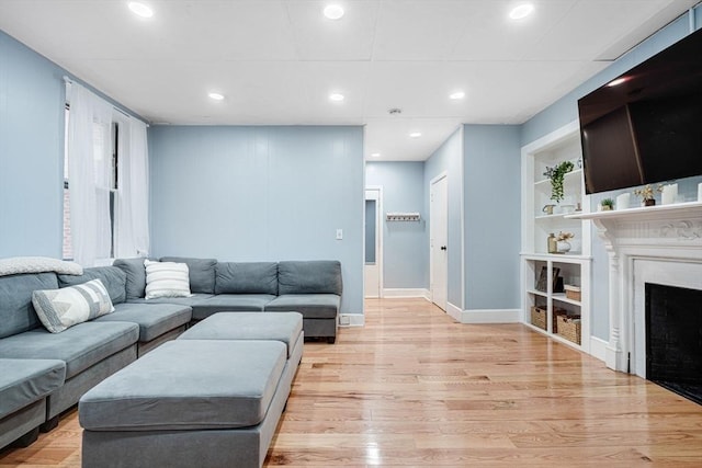 living room with built in shelves and light wood-type flooring