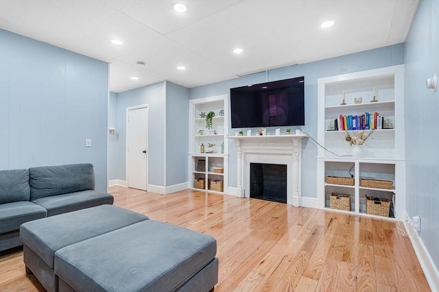 living room with built in shelves and hardwood / wood-style floors