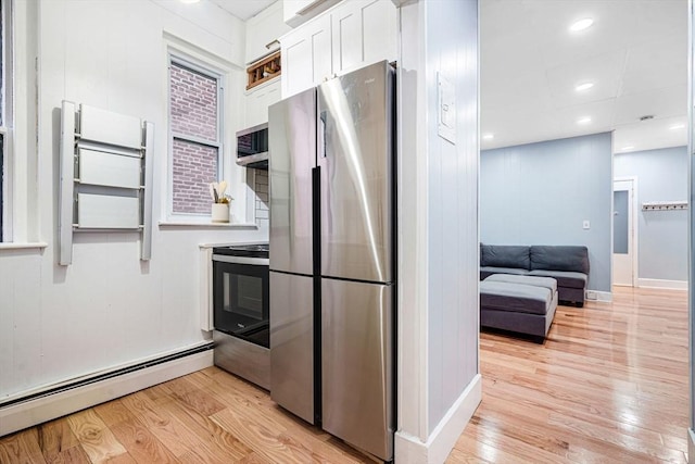 kitchen featuring baseboard heating, white cabinets, stainless steel appliances, and light wood-type flooring