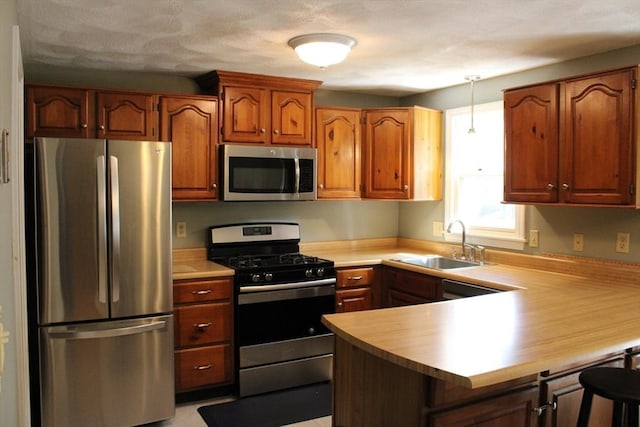 139 Wellman Ave Unit 139, Chelmsford, MA 01863 - kitchen featuring appliances with stainless steel finishes, a peninsula, light countertops, a kitchen bar, and brown cabinetry