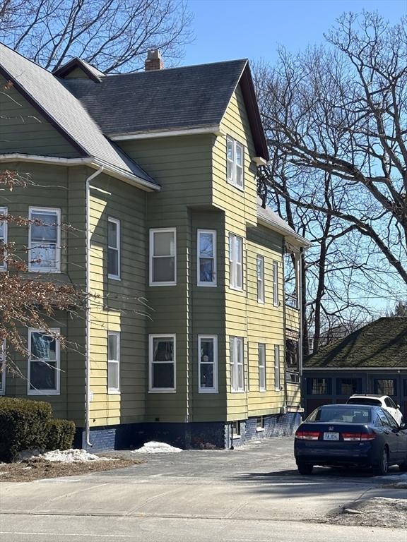 view of side of home with a shingled roof and a chimney