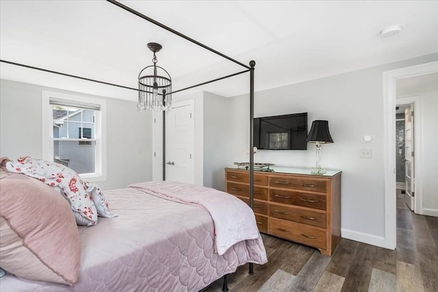 bedroom featuring an inviting chandelier, baseboards, and wood finished floors