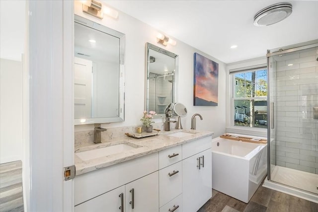 bathroom with a sink, double vanity, a stall shower, and wood finished floors