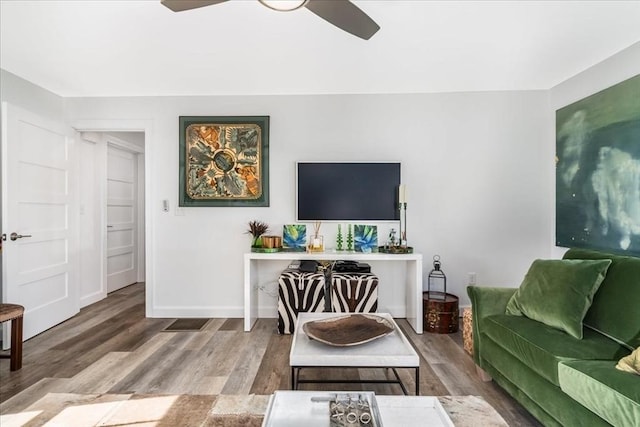 living area with a ceiling fan, baseboards, and wood finished floors