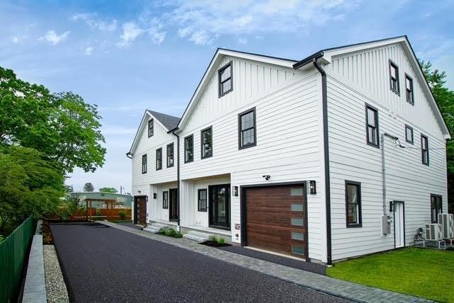 276-278 Nevada Unit 276, Newton, MA 02460 - view of front of home with board and batten siding, an attached garage, and a front lawn