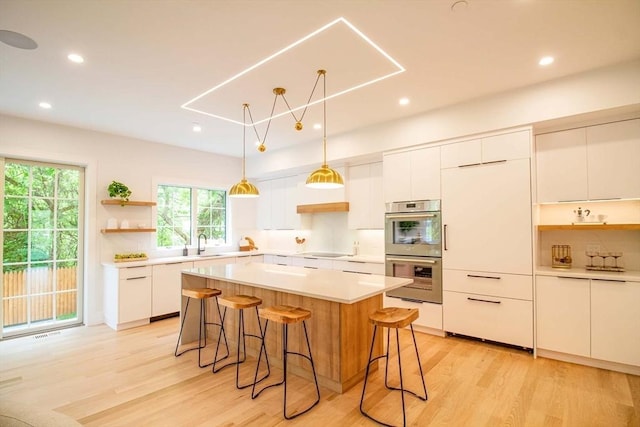 276-278 Nevada Unit 276, Newton, MA 02460 - kitchen featuring open shelves, stainless steel double oven, a kitchen bar, black electric stovetop, and light wood-style flooring