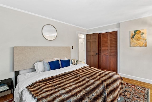 bedroom featuring a closet, baseboards, wood finished floors, and ornamental molding