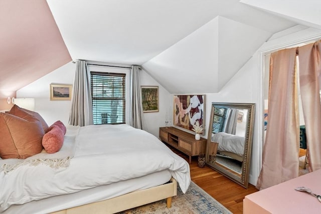 bedroom with lofted ceiling and light wood finished floors