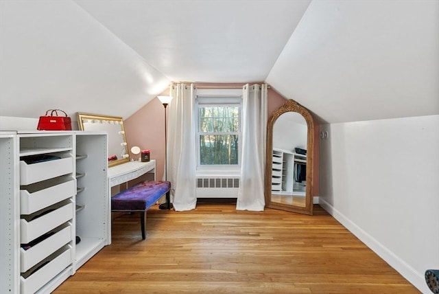 bedroom with baseboards, vaulted ceiling, light wood-style flooring, and radiator heating unit