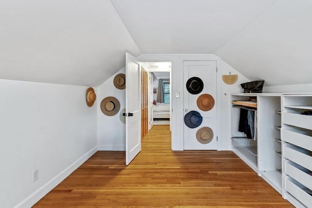 bonus room with baseboards, vaulted ceiling, and light wood-style floors