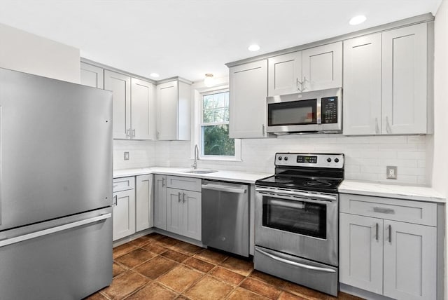 kitchen featuring tasteful backsplash, appliances with stainless steel finishes, gray cabinets, and a sink