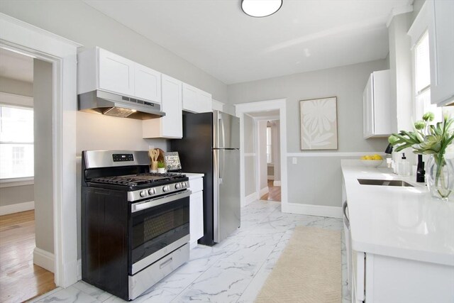 kitchen with stainless steel range with gas cooktop, a wealth of natural light, marble finish floor, and under cabinet range hood