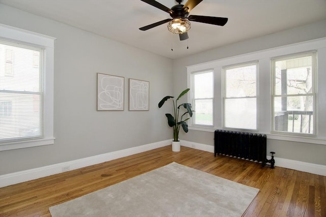 exercise room with radiator heating unit, wood finished floors, and a wealth of natural light