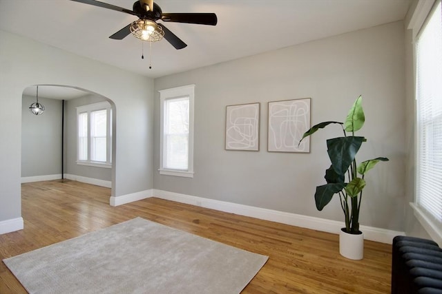 living area with baseboards, radiator heating unit, wood finished floors, and arched walkways