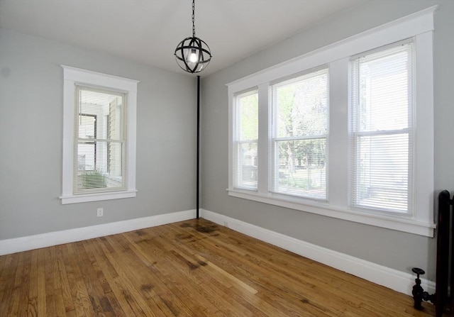 unfurnished dining area featuring a wealth of natural light, wood finished floors, and baseboards