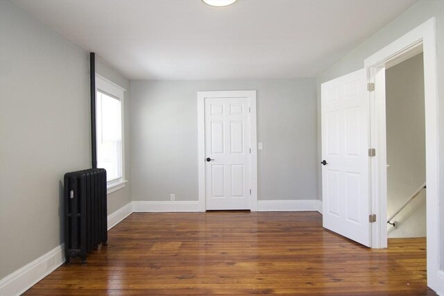 unfurnished room with radiator, baseboards, and wood-type flooring