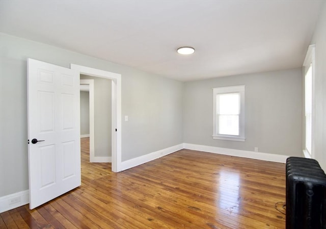 spare room featuring hardwood / wood-style floors, baseboards, and radiator