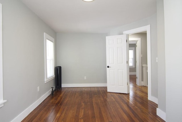 empty room featuring baseboards and dark wood-type flooring