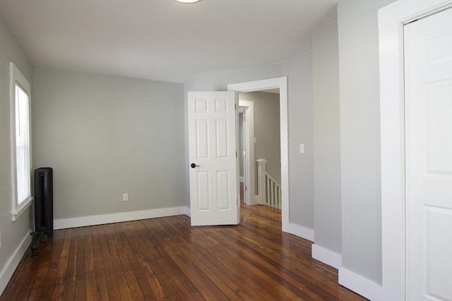 spare room with baseboards and dark wood-type flooring