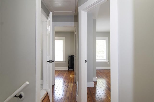 hallway with dark wood finished floors, radiator heating unit, and baseboards